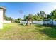 Backyard with playset, green grass, and white fence, on a sunny day at 2408 Bonanza Ln, North Port, FL 34286