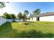 Grassy backyard with a playset, bordered by a white privacy fence and surrounding mature trees at 2408 Bonanza Ln, North Port, FL 34286
