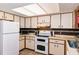 Functional kitchen featuring white cabinets, matching appliances, and a bright skylight at 3261 Rogue St, North Port, FL 34291