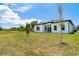 Expansive backyard with lush lawn and modern, white single-story home with covered patio at 398 Sunset N Rd, Rotonda West, FL 33947