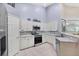 Bright kitchen featuring tile flooring, white cabinetry, and stainless steel appliances at 4225 Fairway Dr, North Port, FL 34287
