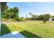 Expansive backyard with lush green grass, mature trees, and a tropical landscaped perimeter, perfect for outdoor activities at 482 Sunset N Rd, Rotonda West, FL 33947