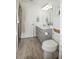 Compact bathroom with wood-look tile flooring, gray vanity, and white toilet at 5009 Skyview Ln, Bradenton, FL 34211