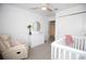 Bedroom featuring white crib, comfortable recliner, wood ceiling fan, and ample natural light at 5009 Skyview Ln, Bradenton, FL 34211