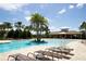 Resort style pool with beach entry, lounge chairs, palm trees, and clubhouse in Harmony at Lakewood Ranch at 5009 Skyview Ln, Bradenton, FL 34211