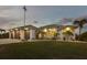 Well-lit home exterior with a three-car garage, lush lawn, and mature landscaping at 530 Spaniards Rd, Placida, FL 33946