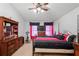 Well-lit bedroom with a ceiling fan, dresser, television, exercise bike and a comfortable bed with red accents at 5510 Moongate Rd, Spring Hill, FL 34606