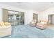 Bright and airy living room with plush blue carpet, comfortable seating, and slider access to the lanai at 6158 Cavan St, Englewood, FL 34224