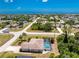 Aerial view of a single-Gathering home with a screened pool, positioned on a corner lot with lush greenery at 7247 Brookhaven Ter, Englewood, FL 34224