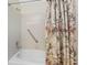 Close up of a bathtub with shower, tiled walls, and floral shower curtain at 7247 Brookhaven Ter, Englewood, FL 34224