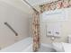 Inviting bathroom showcasing a bathtub with shower, tiled walls, and decorative floral shower curtain at 7247 Brookhaven Ter, Englewood, FL 34224