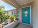 Welcoming front entrance with a teal door, lush landscaping, and tiled flooring at 7247 Brookhaven Ter, Englewood, FL 34224