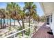 Exterior deck featuring stairs and a railing, leading to the beach, with lovely palm trees at 7420 Manasota Key Rd, Englewood, FL 34223