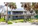 Charming elevated coastal home with a white exterior and a large deck surrounded by palm trees at 7420 Manasota Key Rd, Englewood, FL 34223