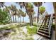 Outdoor stairs leading from sandy ground, with palm trees, up to the home at 7420 Manasota Key Rd, Englewood, FL 34223