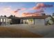 Charming single-story home featuring a spacious driveway, lush landscaping, and a modern, beachy aesthetic at sunset at 7530 Whitcomb St, Englewood, FL 34223