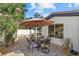 Charming outdoor patio with dining set under a large umbrella, surrounded by tropical plants at 7530 Whitcomb St, Englewood, FL 34223