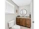 Cozy bathroom features a wooden vanity with a marble countertop, stylish round mirror, and modern toilet at 8005 Bay Pointe Dr, Englewood, FL 34224