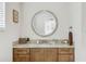 Close-up of a wooden vanity with marble countertop and round mirror in a well-lit bathroom at 8005 Bay Pointe Dr, Englewood, FL 34224