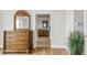 Hallway with wooden floors that leads to a full bathroom, dresser, and tropical plant at 8005 Bay Pointe Dr, Englewood, FL 34224