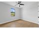 Minimalist bedroom with wood-look floors, neutral walls, a ceiling fan, and a view from the window at 8105 Antwerp Cir, Port Charlotte, FL 33981
