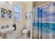 Bright bathroom with a pedestal sink and shower with a decorative ocean themed curtain at 8127 Consul St, Port Charlotte, FL 33981
