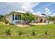 Lovely home showcasing a charming front porch, vibrant lawn and mature palm tree at 8127 Consul St, Port Charlotte, FL 33981