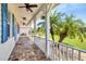 Relaxing front porch view with a swing, ceiling fans, brick pavers, and manicured landscaping at 8127 Consul St, Port Charlotte, FL 33981