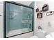 Bathtub with blue tile in the shower with glass doors and decorative shelving on the wall at 8405 Placida Rd # 406, Placida, FL 33946