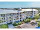Multi-story condominium complex with covered parking, white railings, lush landscaping and mature palm tree at 8411 Placida Rd # 404, Placida, FL 33946