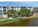 Serene lakeside view of the building, accented by mature trees and a peaceful walking path at 8411 Placida Rd # 404, Placida, FL 33946