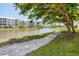Picturesque lakeside view with a walking path shaded by a large tree and colorful buildings in the background at 8411 Placida Rd # 404, Placida, FL 33946