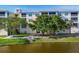 Waterfront building featuring mature trees and lush landscaping around the tranquil lake at 8411 Placida Rd # 404, Placida, FL 33946