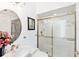 Bright bathroom featuring a shower with gold trim and a vanity with a round mirror at 8500 Manasota Key Rd, Englewood, FL 34223