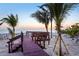Charming wooden walkway with seating, leading to a beautiful beach with swaying palm trees at 8500 Manasota Key Rd, Englewood, FL 34223