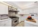 Well-lit kitchen features white cabinets, stainless steel appliances, and an island with cooktop at 8500 Manasota Key Rd, Englewood, FL 34223