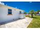 Bright backyard featuring a white home with a concrete patio, bench, and a small palm tree at 859 E 2Nd St, Englewood, FL 34223