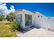 The home's exterior features a quaint patio area, sliding glass doors, fresh landscaping, and a white fence at 859 E 2Nd St, Englewood, FL 34223
