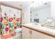 Clean bathroom with a floral shower curtain, cream cabinets, and a large, bright mirror at 9200 Little Gasparilla # 203, Placida, FL 33946