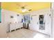 Bright living room with yellow ceiling, white walls, tile floor, a ceiling fan, and access to the balcony at 9200 Little Gasparilla # 203, Placida, FL 33946