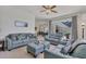 Stylish living room with plush blue sofas, a ceiling fan, and view to lanai at 1002 Rotonda Cir, Rotonda West, FL 33947