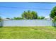 Image shows white fence with green trees and grass in the backyard at 1040 Caples St, Englewood, FL 34223