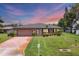 Well-maintained home featuring a lush lawn, a two-car garage, and attractive landscaping under a colorful sky at 1040 Caples St, Englewood, FL 34223