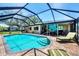 Backyard pool area featuring a screen enclosure, brick patio, and outdoor seating at 1040 Caples St, Englewood, FL 34223