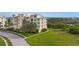 Multi-story tan condo building showing balconies, green lawn, and trees in a beautiful waterfront community at 10521 Amberjack Way # 303, Englewood, FL 34224