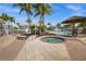View of the spa next to a community pool surrounded by lounge chairs, umbrellas, and lush tropical landscaping at 10521 Amberjack Way # 303, Englewood, FL 34224