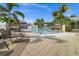 View of the pool with lounge chairs, umbrellas, and lush tropical landscaping at 10521 Amberjack Way # 303, Englewood, FL 34224