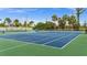 Outdoor tennis court with blue surface and green borders surrounded by lush trees and blue sky at 10521 Amberjack Way # 303, Englewood, FL 34224