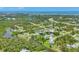 Scenic aerial view of a residential neighborhood with lush greenery, tranquil ponds, and a view of the distant coast at 124 Cutlass Dr, Rotonda West, FL 33947