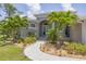 Inviting front entrance with arched doorway, beautiful landscaping, and a winding brick path at 124 Cutlass Dr, Rotonda West, FL 33947